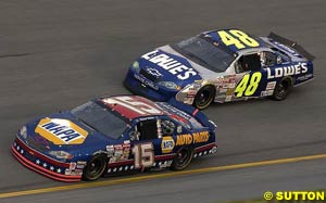 Michael Waltrip runs ahead of Jimmie Johnson