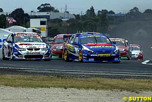 Marcos Ambrose leads Greg Murphy through turn one