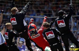 Helio 'Spiderman' Castroneves and his crew climb the front straight fence