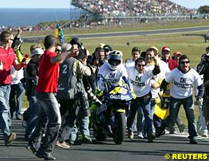 Valentino Rossi is mobbed after winning the race and the 2004 title